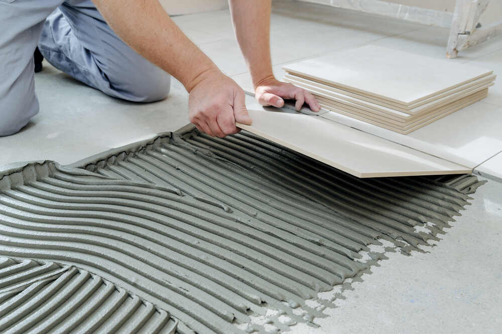 A man laying tile on a floor